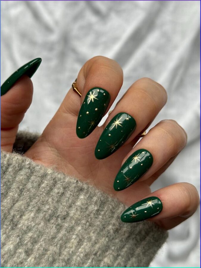 This image showcases a set of nails adorned with a captivating celestial design and shimmering details are artfully placed against a deep green base. #darkgreenmanicure #celestial #nailart