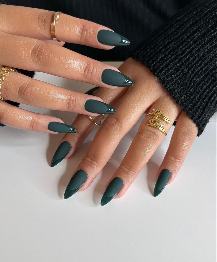 Almond-shaped nails painted in a deep forest green, with a mix of matte and glossy finishes. #forestgreennails #almondnails #mattenails