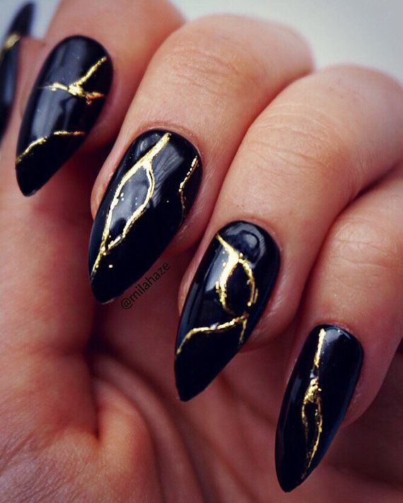 Bold black and gold nails with a glamorous design, featuring a sleek black base accented by shimmering gold details, ideal for luxe baddie nail ideas.