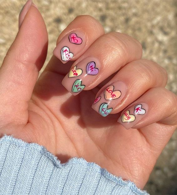 Festive Valentine's Day nails featuring colorful conversation hearts.