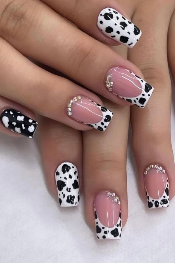 Nails painted with a classic cow print design, a fun Western nail art idea. #cowprintnails #westernnails #nailart